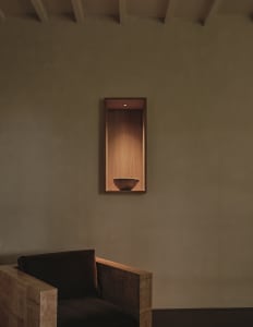 Cozy room with a wooden bench, a wooden bowl on a shelf, and a brown color scheme, lit by dim lighting