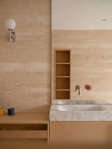 Bathroom with a white sink, wooden cabinet, and beige color scheme, lit by natural light