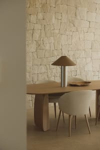 A modern dining room with a wooden table and chairs surrounded by a stone wall, well-lit and inviting