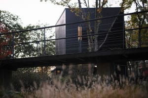 A calm and serene black and white photograph of a house with a metal deck and a black roof, taken from a low angle looking up at the structure