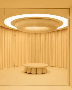 Bright and inviting dining space with a cream-colored fabric-covered wall, a large white circular table, and a warm atmosphere