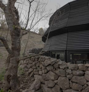 A dark and mysterious building with a stone exterior and a large circular structure, set against a contrasting background