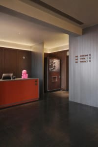 A small office or break room with a desk, pink stuffed animal, and refrigerator, featuring a cozy and inviting atmosphere