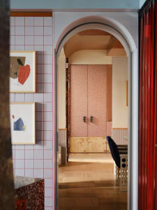 A cozy dining room with a pink door, a chair, and a dining table on a wooden floor, with an inviting atmosphere