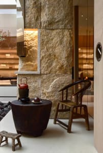 Cozy living space with a wooden chair and table near a rock wall, featuring a combination of natural and man-made elements