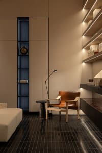 Cozy living room with a couch, chair, and lamp, set against a dimly lit background with a wooden floor