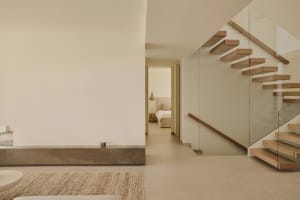 Cozy bedroom with a white wall, brown floor, and a bed in the corner, featuring a rug and a cup on the floor
