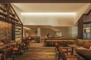 Cozy restaurant with wooden floors, high ceiling, and a mix of natural and artificial lighting, featuring multiple seating options and a warm ambiance