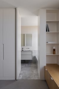 A modern bathroom with a white sink, mirror, and cabinet, well-lit by natural light from a window