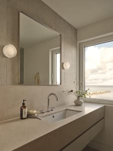 Bathroom with a marble sink, large mirror, and natural light from a window