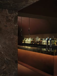 A well-stocked bar with a marble countertop, bottles of liquor, and a sink, creating a cozy atmosphere for socializing and enjoying drinks