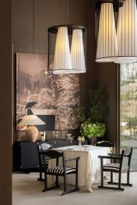 Dining room with a table set for a meal, surrounded by chairs, wine glasses, and vases, with a large painting on the wall in a well-lit, modern space