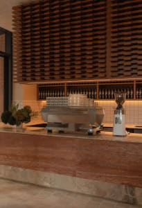 A dimly lit kitchen with a wooden theme, featuring a counter with various items and a coffee machine, in a restaurant or cafe setting