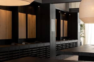 A dimly lit modern kitchen with a wooden floor, black counter, and wooden cabinets and drawers