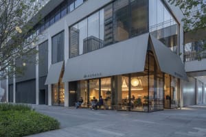 A modern cafe with a glass front, comfortable seating, and natural light, featuring chairs and dining tables