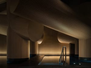 A calm and relaxing pool area surrounded by wooden walls and a railing, with warm and natural lighting