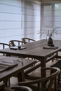 A warm and inviting dining area with a wooden table and chairs, surrounded by a potted plant and natural light
