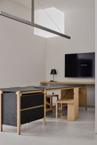 Cozy home office with a wooden desk, flat screen TV, and computer setup, surrounded by a few personal items