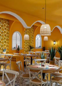 Cozy restaurant with a modern style, warm yellow and orange color scheme, and dim lighting, featuring white furniture and potted plants
