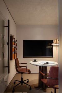 A modern study with a brown chair, wooden table, and glass surfaces, well-lit with natural light from windows