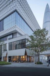 A modern office space with a large glass facade, natural light, and comfortable furniture