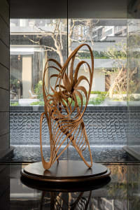 A modern room with a glass wall and a wooden sculpture in front of it, placed in a visually appealing artistic setting