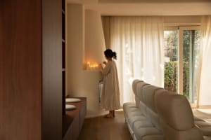 Bathroom with a sink on the left, a mirror above it, and a couch on the right, well-lit and inviting