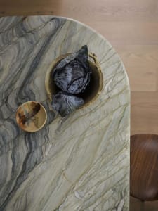 A photograph of a marble countertop with a bowl placed on it, set in a kitchen or dining area with natural or ambient lighting