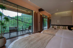 Cozy bedroom with a white-covered bed, a chair, and a dining table, featuring a large window with natural light