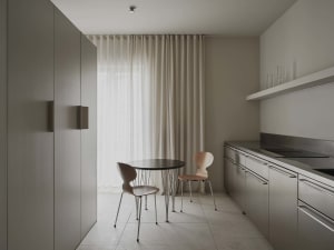 A well-lit modern kitchen and dining area with a wooden table and chairs, a sink, refrigerator, and window