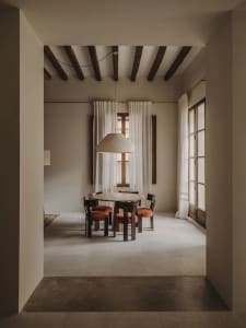 A dimly lit dining room with a wooden table and chairs, surrounded by other furniture, creating a cozy atmosphere