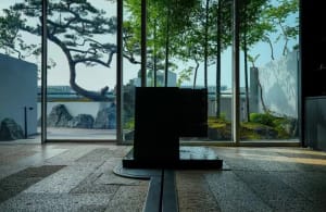 A calm and serene modern room with a large black square art piece, minimalist decor, and natural light from a large window
