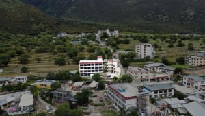 A picturesque town surrounded by mountains with a mix of residential and commercial buildings, featuring various architectural styles and materials, lit by natural daylight