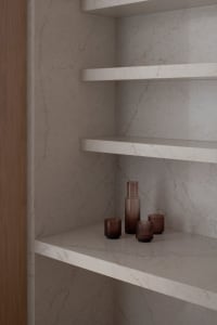 A modern bathroom with a white marble countertop featuring three brown bottles arranged in a neat line, under soft and warm lighting