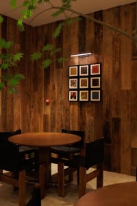 Dining room with wooden walls and a wooden dining table, surrounded by black chairs in a dimly lit space
