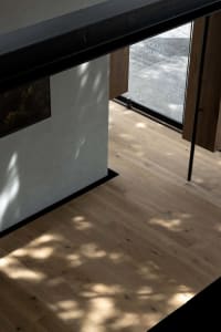 Bright and inviting kitchen with wooden floors, a white wall, a sink, a refrigerator, and natural light from a window