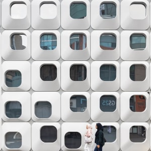 Photograph of a modern building with a white facade featuring a unique pattern of small windows, giving a clean and minimalist appearance