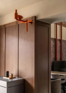 Dining room with a wooden wall, a brown wooden door, a dining table, chairs, a cup, a bowl, and a vase, creating a warm and cozy atmosphere