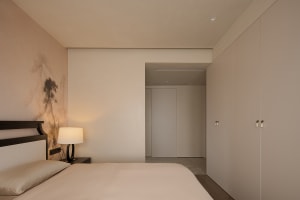 A calm and inviting bedroom with a bed, a table, and a door, featuring a neutral color scheme and minimal decor