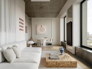 Cozy modern living space with a couch, dining table, and TV, decorated with a vase, bowl, and book, under dim lighting