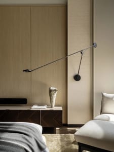 Cozy bedroom with a bed, dresser, and lamp, featuring a wooden floor and tan color scheme, with natural light from a window