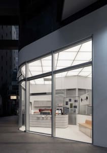 Well-lit modern kitchen with a white color scheme, stainless steel countertops, and a large window allowing natural light