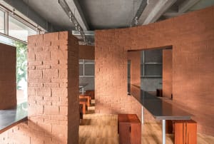 A modern dining space with a brick wall, wooden floor, and natural light from a window, featuring a dining table and chairs