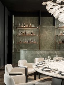 Cozy restaurant dining area with a round table, marble-like countertop, and dim lighting, surrounded by chairs and wine glasses
