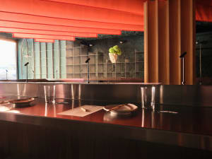 A modern restaurant with a wooden theme, featuring a dining table, vases, and potted plants, creating an inviting and comfortable atmosphere
