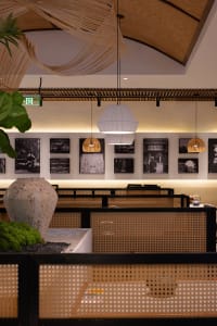 A modern restaurant interior with tables, chairs, artworks, and hanging lights creating a warm and inviting atmosphere