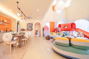 Vibrant living room with colorful furniture, a couch, chair, potted plant, dining table, and natural light from windows