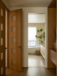 Bathroom with a wooden door, white bathtub, sink, and natural light from a window