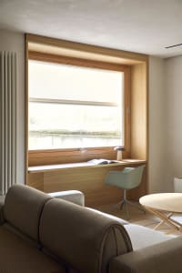A well-lit living room with a couch, chair, and dining table, featuring wood and fabric materials and a cozy atmosphere