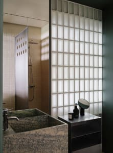 Modern bathroom with a marble sink, a shower, and a mirror above the sink, set against a green color scheme